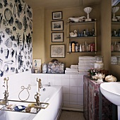 Verspielte Gestaltung im Bad mit Muschelmotiven auf Tapete an Wand und Ablage mit Engelmotiven aus Metall auf Badewanne