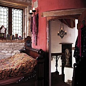 Antikes Bett im rustikalen Raum mit roter Wand und offene Tür zum Treppenhaus