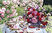 Rosa und rote Rosen in der Vase auf Tisch mit antikem Silberservice