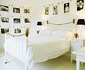 Schwarz-weiß Fotografien an Wänden und Doppelbett mit altem Messinggestell und Spitzenbettwäsche