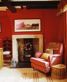 Gemusterter roter Sessel neben Kamin im traditionellen Wohnzimmer mit roten Wänden
