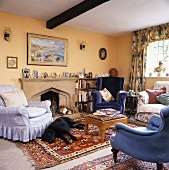 Verschiedenfarbige Sessel in apricotfarbenen Wohnzimmer mit Kamin und gemustertem Teppich