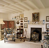 Blau gemusterte Sessel im ländlichen Wohnzimmer mit weißer Balkendecke und Kamin