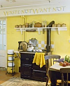 Alte gelb getönte Küche mit Tontöpfen auf Konsole über antiken Küchenofen