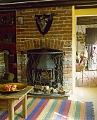 Gestreifter Teppich vor gemauertem Kamin mit gusseisernem Ofen im Wohnzimmer