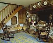 Schaukelstühle vor Kamin in Ziegelwand und Holztreppe im alten Wohnraum