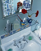 Glasablage und Spiegel über weißes Waschbecken vor blauer Wand