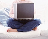 A woman sitting on a sofa with a laptop