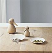 Two wooden birds, sunflower seed and pumpkin seeds on a table