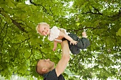 A father holding his little daughter above his head
