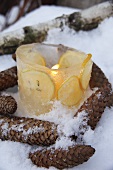 A burning candle in a ice cream bowl decorated with lemon slices