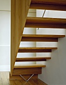 A wooden staircase and banister rail leading up from wooden floorboards