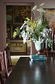 Vase mit Kräuterblüten auf einem Bücherstapel auf dem Esstisch