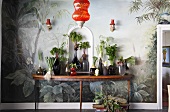 Assorted vegetables in glass vases on a console table in front of a painted wall
