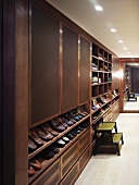 Men's dressing room with built-in wardrobe made of dark wood and shelves for shoes