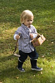 Boy carrying hand hoe tool and small basket