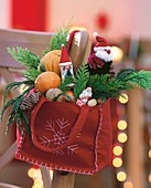 Red felt bag filled with Father Christmases, mandarins and nuts