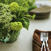 Tisch mit Blumenstrauss, Servietten und Gabeln