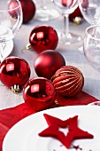 Rote Weihnachtskugeln auf gedecktem Tisch