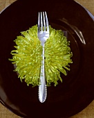 Eine Gabel auf einer Chrysantheme auf schwarzem Teller