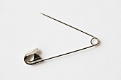 An open safety pin in front of a white background