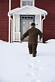 Man walking to house through deep snow