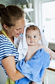 Mutter trocknet Baby mit Handtüchern ab