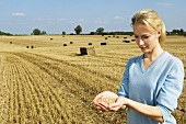 A woman in a field holding grains of wheat