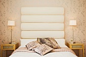 Stilvolles Schlafzimmer mit Doppelbett, grossem Kopfteil, Zierkissen & Nachtischchen mit Tischleuchten