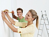Young couple using measuring tape on wall