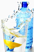 Zitrone fällt in Glas Mineralwasser