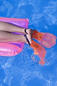 Feet in flippers on an airbed in water