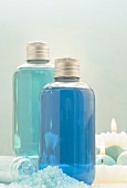 Badesalz und Badezusätze in Flaschen, im Hintergrund Kerzen