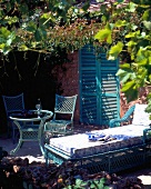 Table, chairs and lounger under canopy of leaves
