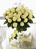 Vase of white roses with gifts