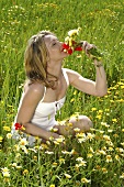 Young woman in a meadow sniffing a bunch of flowers