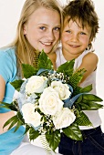 Boy and girl holding bouquet of white roses