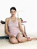 Woman in underwear sitting on rug in front of sofa
