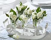 White roses in wine glasses on a tray