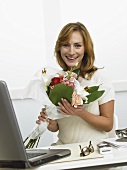 Frau mit Blumenstrauss am Schreibtisch