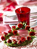 Heart-shaped wreath of red roses beside place-setting