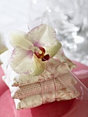 Drei kleine Kissen mit Band und Orchideenblüte auf Teller