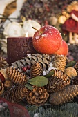 Weihnachtsdeko mit Zapfen, roten Äpfeln und Kerze