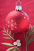 Red Christmas tree bauble on embroidered linen cloth