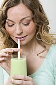 Woman drinking cucumber shake through a straw