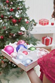 Woman holding box of Christmas baubles