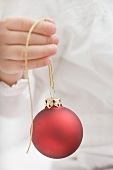 Child holding Christmas bauble with gold string