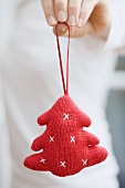 Hand holding knitted Christmas tree ornament