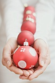 Hands holding red Christmas baubles