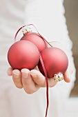 Hand holding red Christmas baubles